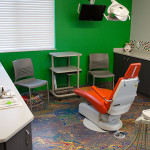 image of pediatric dental room with green walls and orange dentist chair